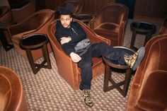 a man sitting on top of a chair in a room filled with brown velvet chairs