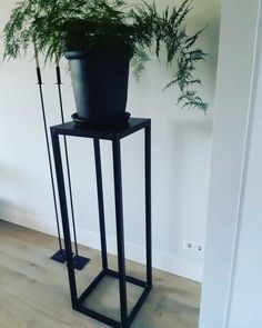 a tall black plant stand holding a potted plant