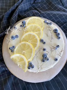 a cake decorated with lemons and blueberries on a plate