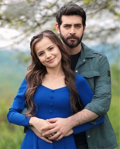 a man and woman standing next to each other in front of a tree with flowers