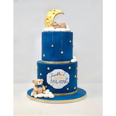 a three tiered blue cake with a teddy bear on top and the moon above it