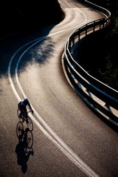 a man riding a bike down a curvy road