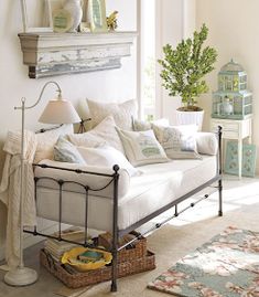 a living room with a white couch and lots of pillows on top of the bed