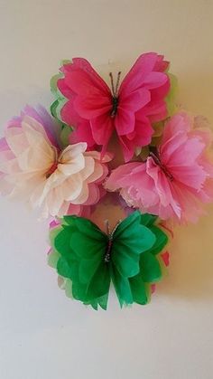 several pink and green paper flowers on a white surface