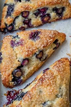 blueberry scones on a baking sheet with powdered sugar and crumbs