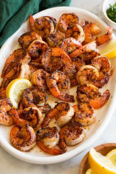 grilled shrimp with lemon wedges on a white platter