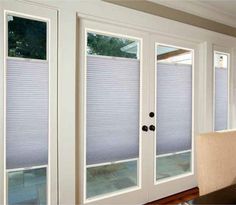 a living room filled with furniture and windows covered in cellular shades on the sliding glass doors