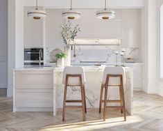 two stools sit in front of an island with marble countertops and white cabinets