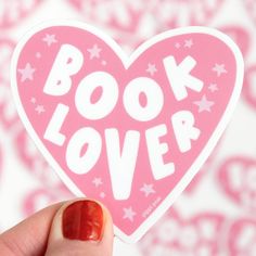 a person holding up a pink sticker with the words book lover written on it