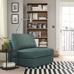 a living room filled with furniture and bookshelves next to a window on top of a hard wood floor