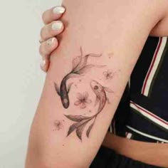 a woman's arm with a fish tattoo on the left side of her arm