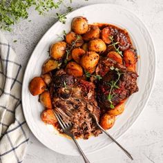 a white plate topped with meat and potatoes