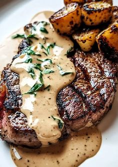 grilled steak, potatoes and gravy on a white plate with garnish