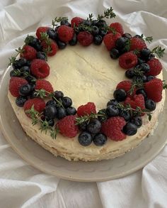 a cake decorated with berries and greenery on a plate