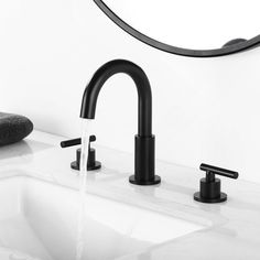 a black faucet and sink in a bathroom with a round mirror above it