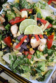 a salad with chicken, lettuce, corn, and tomatoes on a plate