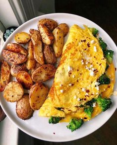 an omelet, potatoes and broccoli on a white plate