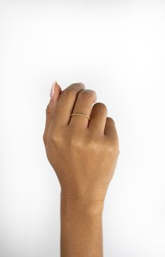 a woman's hand with a gold ring on her left wrist and the middle finger