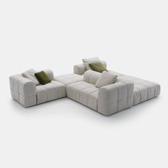 a white couch with two green pillows on the back and one in the middle, sitting next to each other