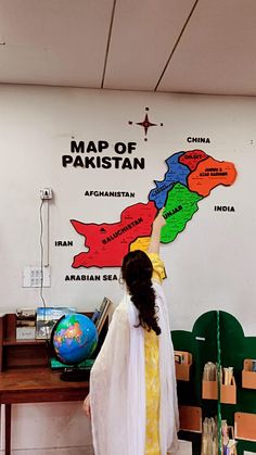 a woman pointing at a map on the wall