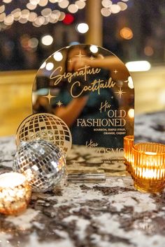 a table topped with a disco ball next to a glass candle holder and some lights