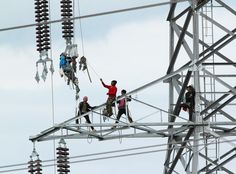 several people climbing up and down an electrical tower