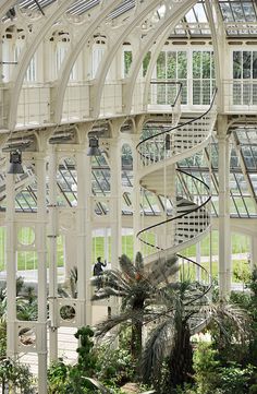 the inside of a large building with lots of windows and plants growing in front of it