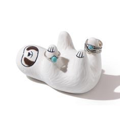 a white ceramic animal with two rings on it's nose and eyes, laying down