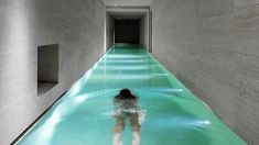 a woman is standing in the middle of a long hallway with water running down it