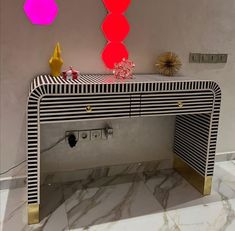 a white and gold console table with red, yellow, and pink lights above it