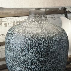 a black and white vase sitting on top of a table next to a light fixture