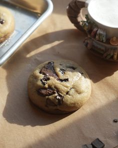 a chocolate chip cookie sitting on top of a table next to a baking pan and spatula