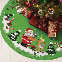 a green christmas rug with santa clause and reindeers on it next to a tree