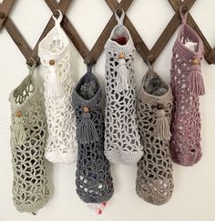 five crocheted bags hanging on a wooden rack with tassels attached to them