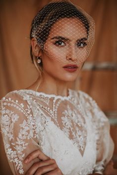 a woman in a white dress with a birdcage veil on her head and shoulder