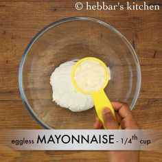 someone is mixing eggs in a bowl with a measuring spoon to make mayonnaise