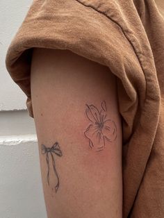 a woman with a tattoo on her arm has a flower and a bow in it