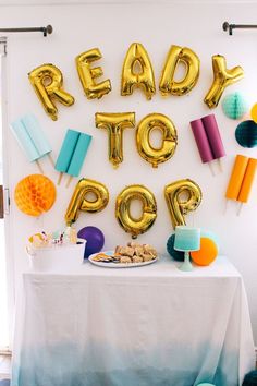 a table topped with balloons and cake next to a sign that says ready to pop