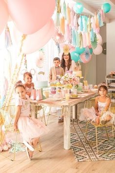 a group of children sitting around a table with balloons