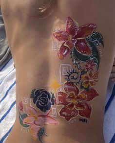 the back of a woman's body with flowers painted on her stomach and chest