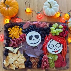 a tray filled with halloween food and decorations on top of a wooden table next to pumpkins