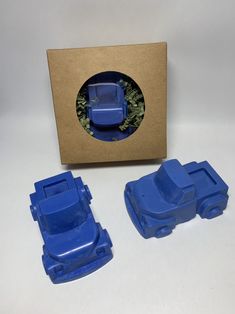 two blue plastic cars sitting in front of a cardboard box