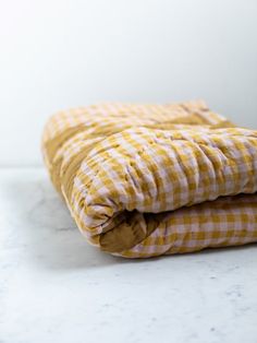 two yellow and white checkered blankets folded on top of each other in front of a white wall