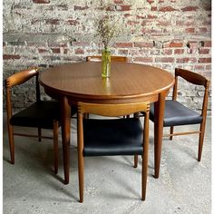 a wooden table with two chairs and a vase filled with flowers on top of it