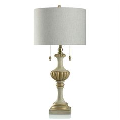 a lamp with a white shade on top of it and a gold finish around the base