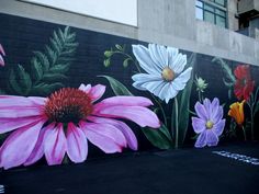 a mural painted on the side of a building with flowers and leaves in it's center