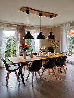 a dining room table with black chairs and hanging lights