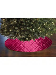 a christmas tree in a pink basket on a wooden floor