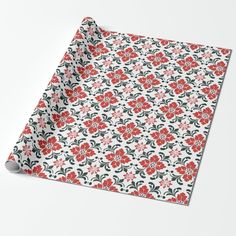 a red and black floral pattern wrapping paper on a white tablecloth with an orange flower in the center