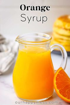 an orange syrup in a glass pitcher next to some pancakes on a table with text overlay